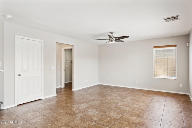 empty room featuring ceiling fan, a smoke detector, and baseboards