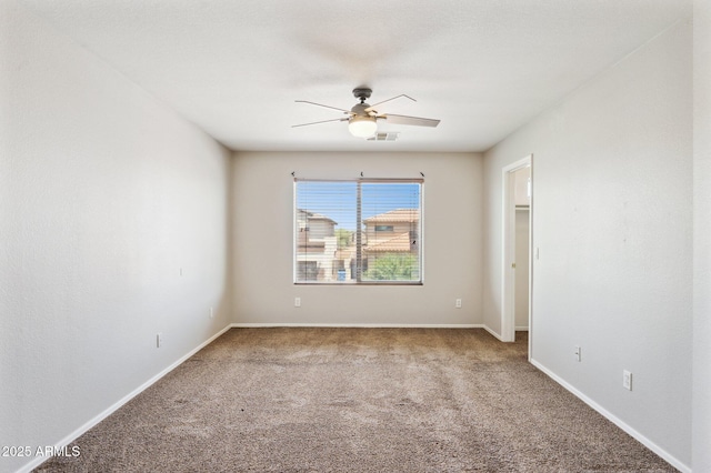 carpeted spare room with a ceiling fan and baseboards