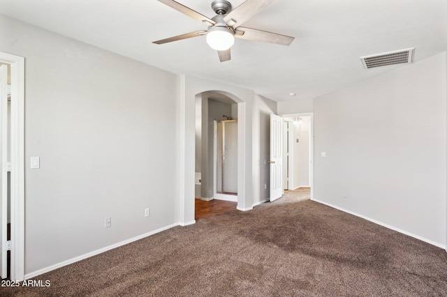 carpeted spare room featuring arched walkways, ceiling fan, and baseboards