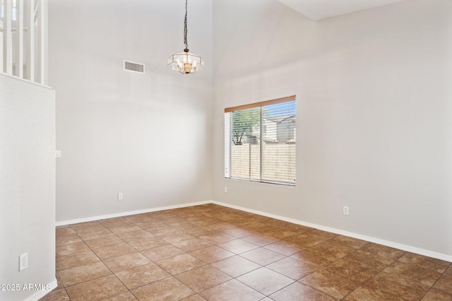 unfurnished room featuring a chandelier, a high ceiling, tile patterned floors, and baseboards