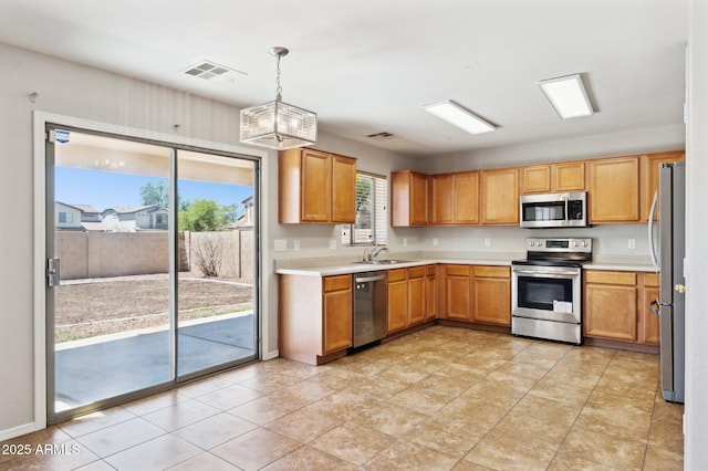 kitchen featuring appliances with stainless steel finishes, a sink, light countertops, pendant lighting, and light tile patterned floors