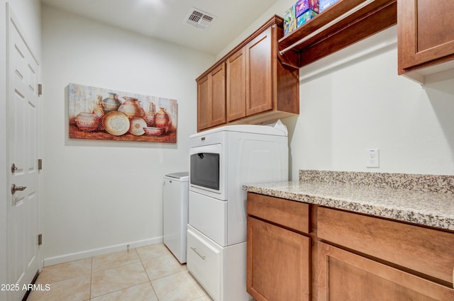 clothes washing area with cabinets, separate washer and dryer, and light tile patterned floors