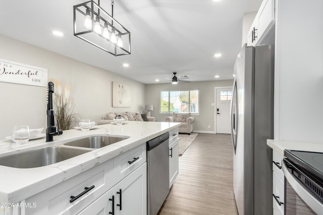 kitchen with appliances with stainless steel finishes, light stone counters, ceiling fan, pendant lighting, and white cabinets