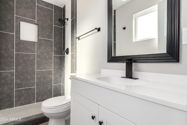 bathroom with toilet, vanity, and tiled shower