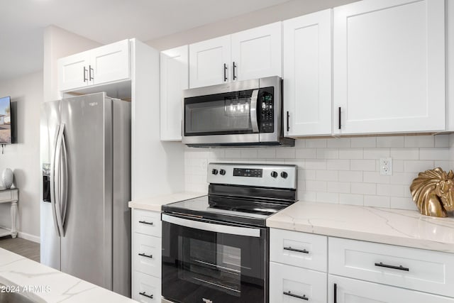 kitchen with stainless steel appliances, white cabinetry, tasteful backsplash, and light stone counters