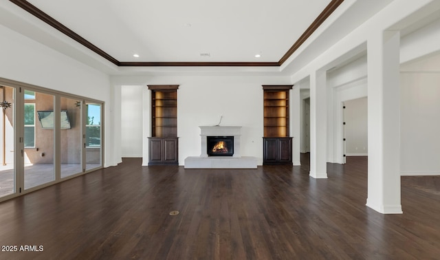 unfurnished living room featuring dark hardwood / wood-style floors, a raised ceiling, ornamental molding, and built in shelves