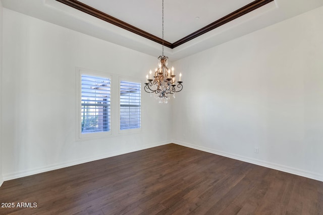 empty room with dark hardwood / wood-style flooring, a tray ceiling, an inviting chandelier, and crown molding