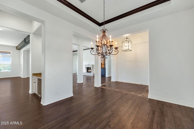 unfurnished dining area with a raised ceiling, crown molding, a chandelier, and dark hardwood / wood-style floors