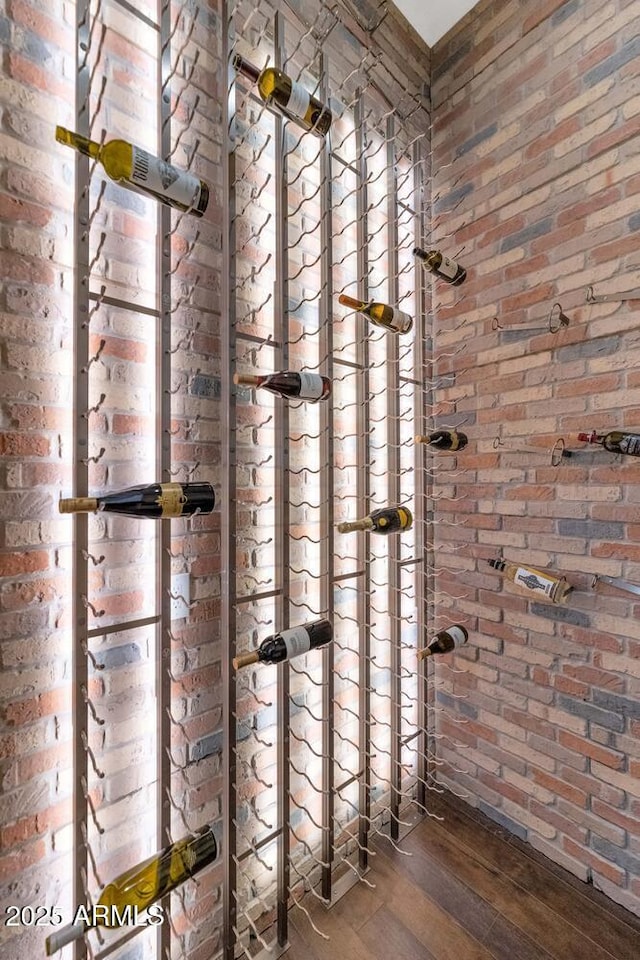 wine room with hardwood / wood-style floors and brick wall