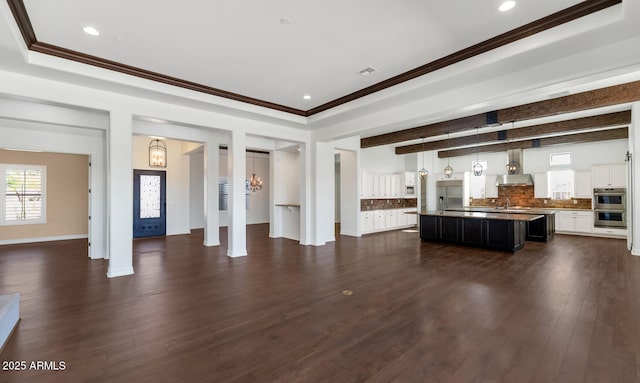 unfurnished living room with ornamental molding, an inviting chandelier, and dark wood-type flooring