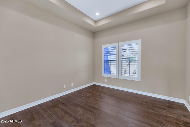 unfurnished room with a raised ceiling and dark hardwood / wood-style flooring