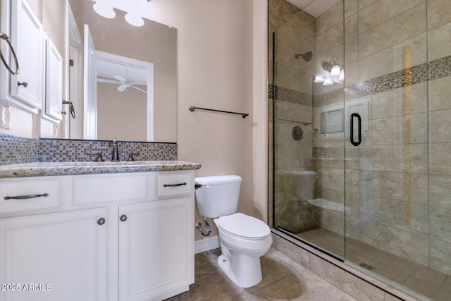 bathroom featuring vanity, a shower with door, ceiling fan, toilet, and tasteful backsplash