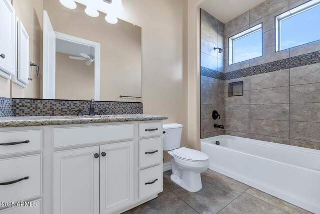 full bathroom featuring toilet, vanity, backsplash, and tiled shower / bath combo