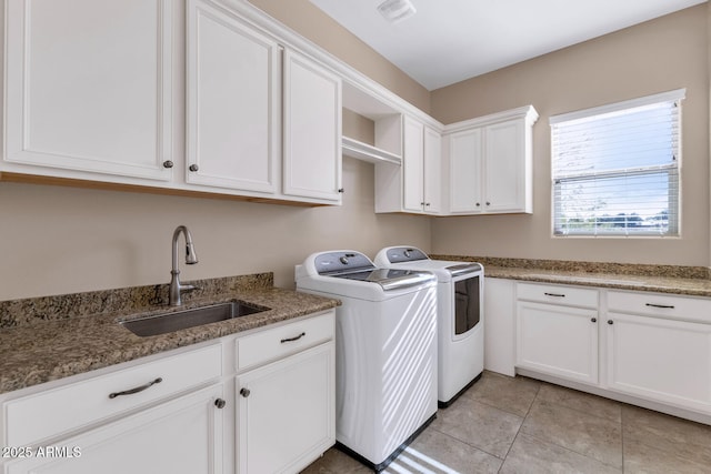 laundry room featuring cabinets, light tile patterned floors, sink, and washing machine and clothes dryer