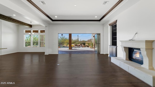 unfurnished living room featuring a chandelier, dark hardwood / wood-style floors, a raised ceiling, and crown molding