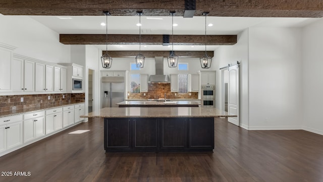 kitchen with built in appliances, a large island, a barn door, and pendant lighting