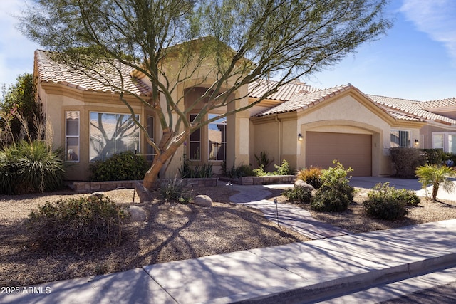 mediterranean / spanish home with a garage, a tiled roof, and stucco siding