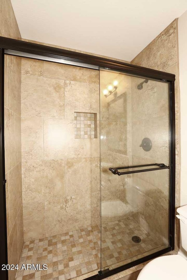 bathroom with a shower with shower door and toilet