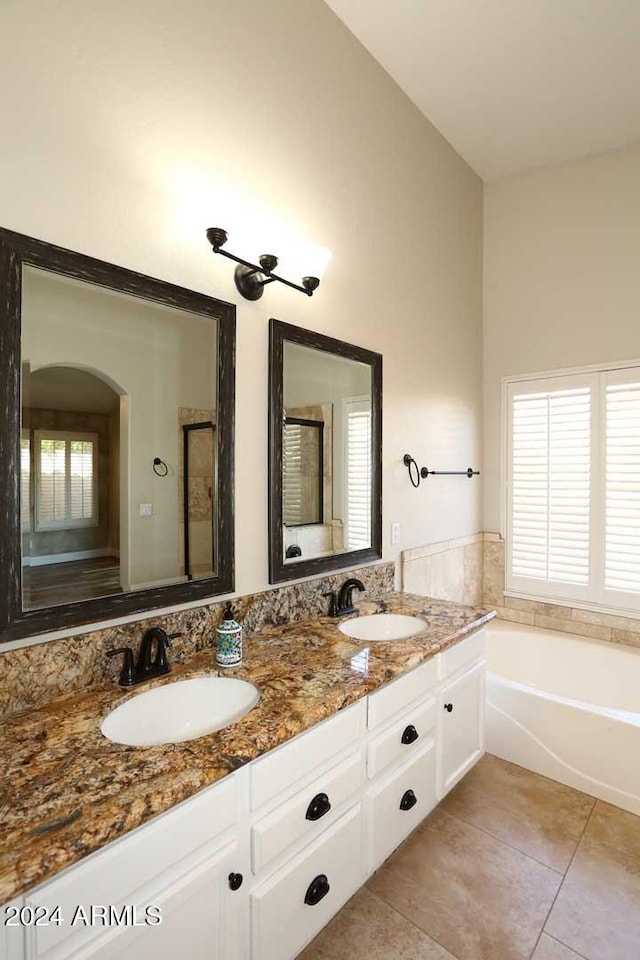 bathroom with a bath, vanity, tile patterned floors, and a healthy amount of sunlight