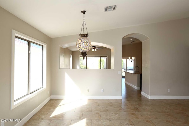 empty room featuring ceiling fan with notable chandelier