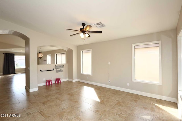 empty room featuring plenty of natural light and ceiling fan with notable chandelier