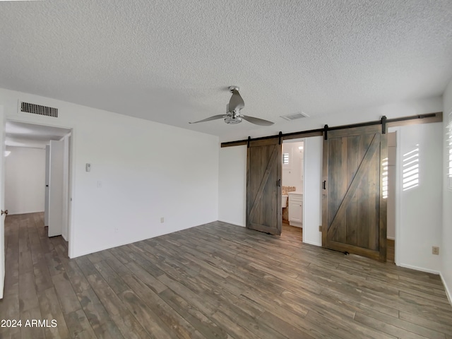 interior space featuring ceiling fan, wood-type flooring, a textured ceiling, and a barn door