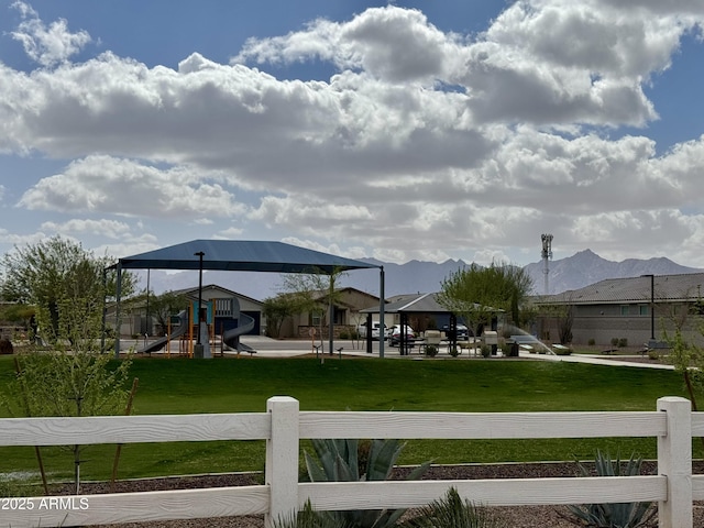 view of yard featuring playground community, a gazebo, fence, and a mountain view