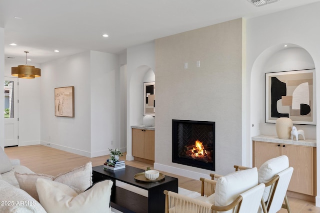 4301 E Sells Dr, Phoenix, AZ 85018 - living room featuring light wood finished floors, arched walkways, recessed lighting, baseboards, and a warm lit fireplace
