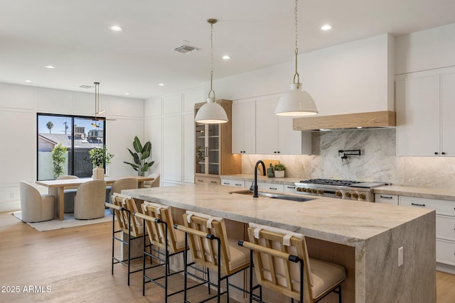 4301 E Sells Dr, Phoenix, AZ 85018 - kitchen featuring a sink, light wood-type flooring, a large island with sink, decorative backsplash, and stove