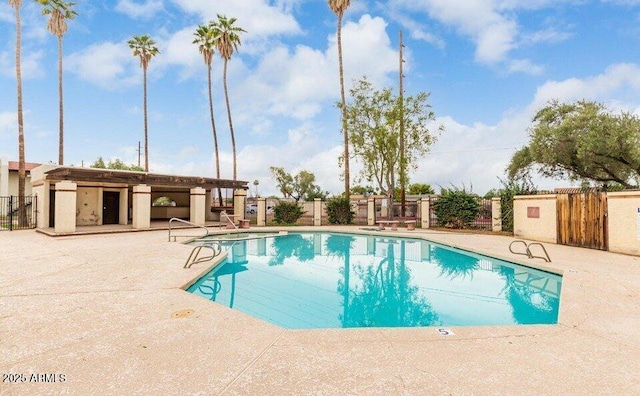 community pool with a patio area and fence