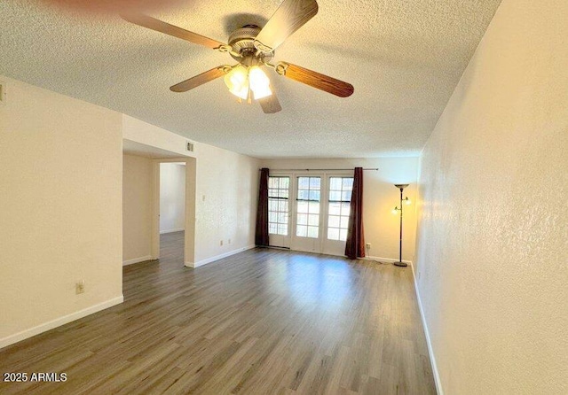 empty room featuring ceiling fan, a textured ceiling, baseboards, and wood finished floors