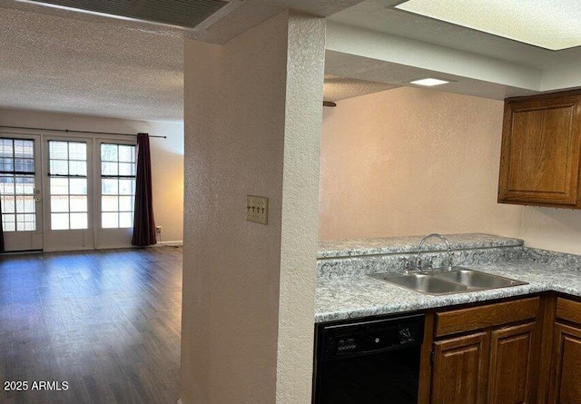 kitchen featuring dishwasher, wood finished floors, light countertops, a textured ceiling, and a sink