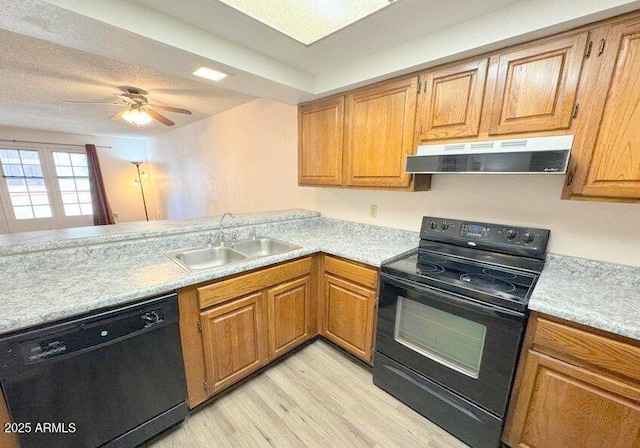 kitchen with light wood-style flooring, extractor fan, light countertops, black appliances, and a sink