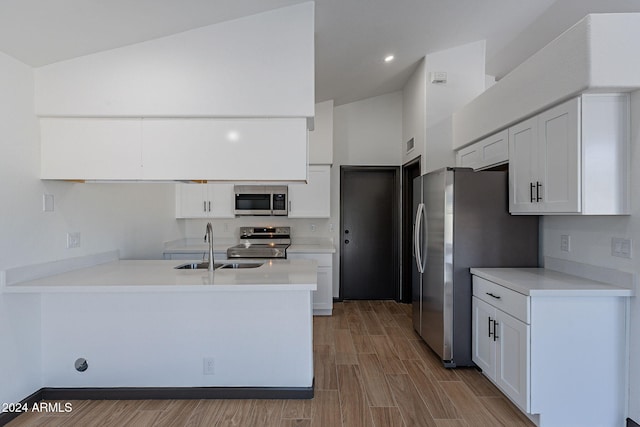 kitchen featuring white cabinetry, stainless steel appliances, and vaulted ceiling