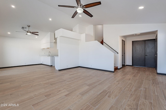 unfurnished living room featuring sink, light hardwood / wood-style floors, and lofted ceiling