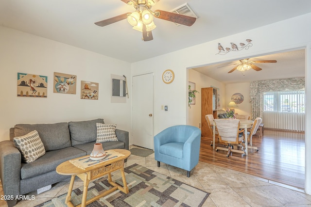 living area featuring a ceiling fan, visible vents, and light tile patterned floors