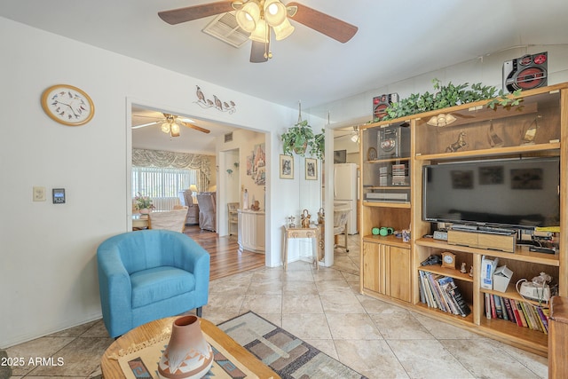 living room with light tile patterned floors, visible vents, and a ceiling fan