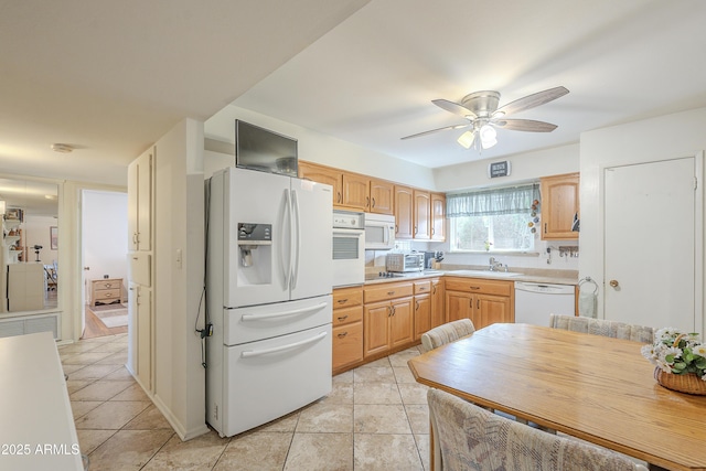 kitchen featuring light tile patterned floors, light countertops, light brown cabinetry, a sink, and white appliances