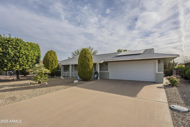 ranch-style house featuring stucco siding, a shingled roof, solar panels, a garage, and driveway