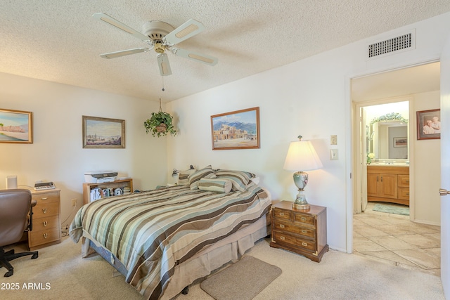 bedroom featuring a ceiling fan, visible vents, a textured ceiling, and light colored carpet