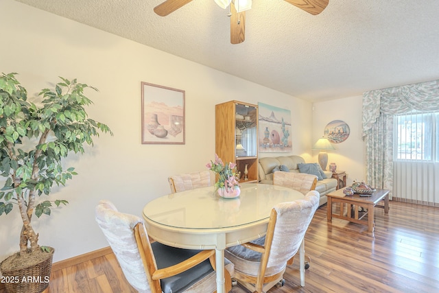 dining area with ceiling fan, a textured ceiling, baseboards, and wood finished floors