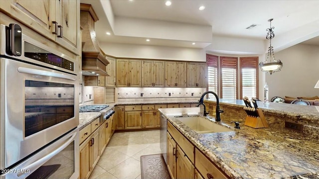 kitchen featuring sink, light stone counters, decorative light fixtures, light tile patterned floors, and appliances with stainless steel finishes