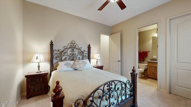 bedroom with ensuite bath, light colored carpet, and ceiling fan