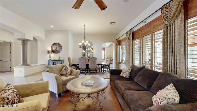 living room featuring ceiling fan with notable chandelier, a healthy amount of sunlight, decorative columns, and light hardwood / wood-style flooring