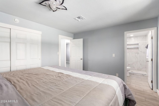 bedroom with light hardwood / wood-style floors, a closet, and ensuite bath