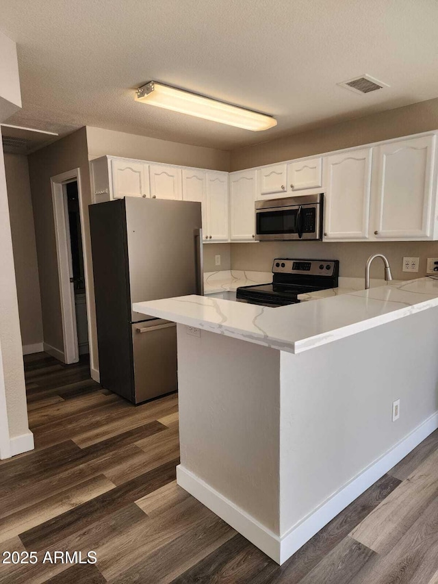 kitchen with a peninsula, visible vents, appliances with stainless steel finishes, and white cabinets