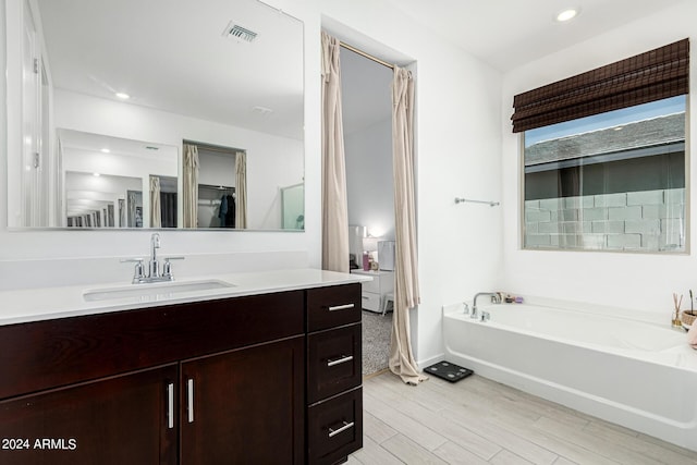 3454 E Jasmine Way, San Tan Valley, AZ 85143 - bathroom featuring visible vents, recessed lighting, wood finished floors, a bath, and vanity