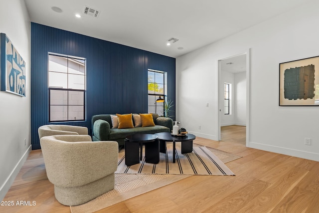 living area featuring baseboards, light wood-style flooring, and visible vents