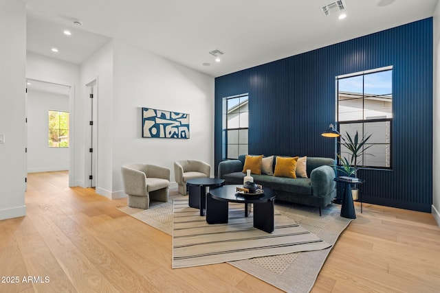living area with baseboards, visible vents, and light wood-style floors