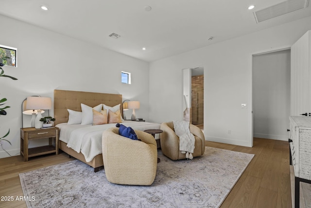 bedroom with baseboards, visible vents, multiple windows, and wood finished floors